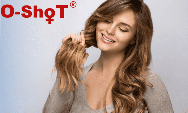Healthy woman with long wavy hair smiling and touching her hair at Performance Pain and Sports Medicine clinic.
