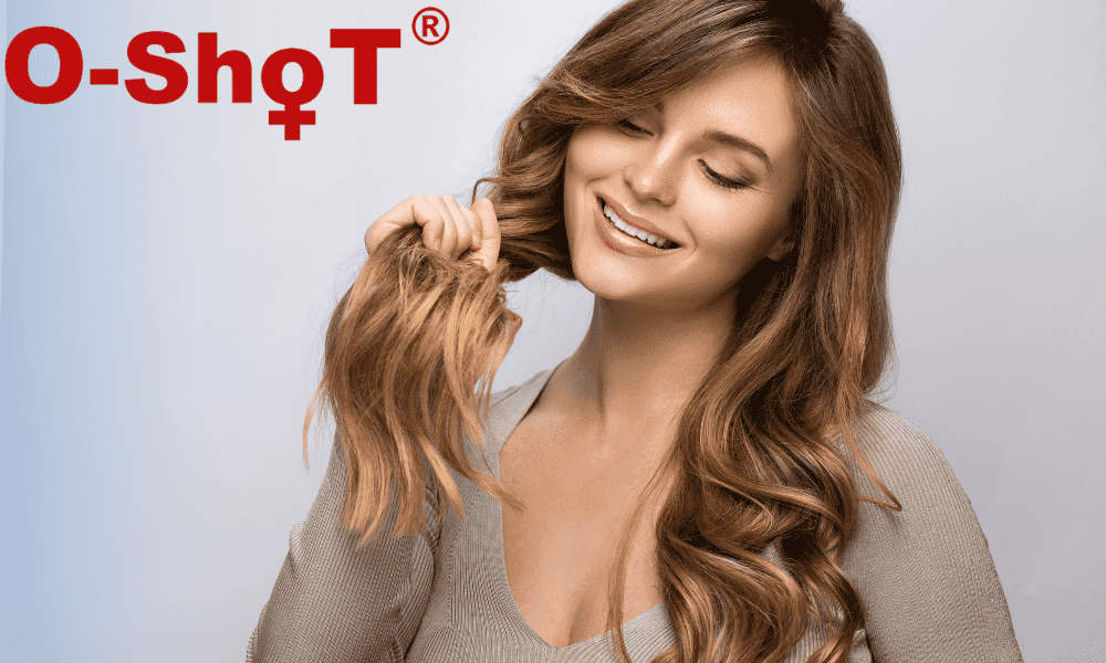 Healthy woman with long wavy hair smiling and touching her hair at Performance Pain and Sports Medicine clinic.
