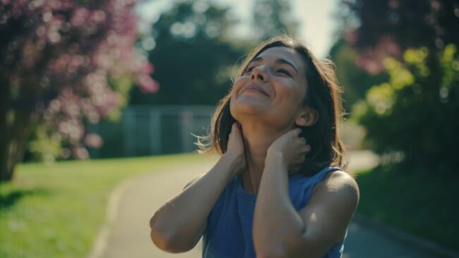 2804550 Relieved woman stretching neck outdoors after pain relief, demonstrating successful sports medicine treatment for neck and shoulder pain.