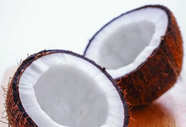 2250079 Fresh coconut sliced open, highlighting its white flesh and textured brown shell for healthy nutrition and natural energy.