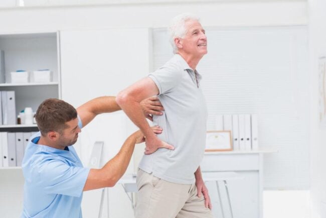 2454498 Chiropractic treatment for senior man with back pain at healthcare clinic.
